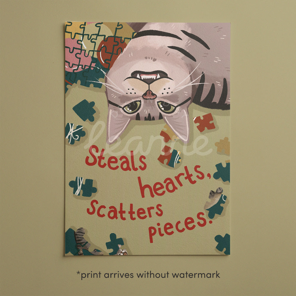 Unframed cat puzzle artwork featuring puzzle pieces and the words “Steals hearts, scatters pieces”