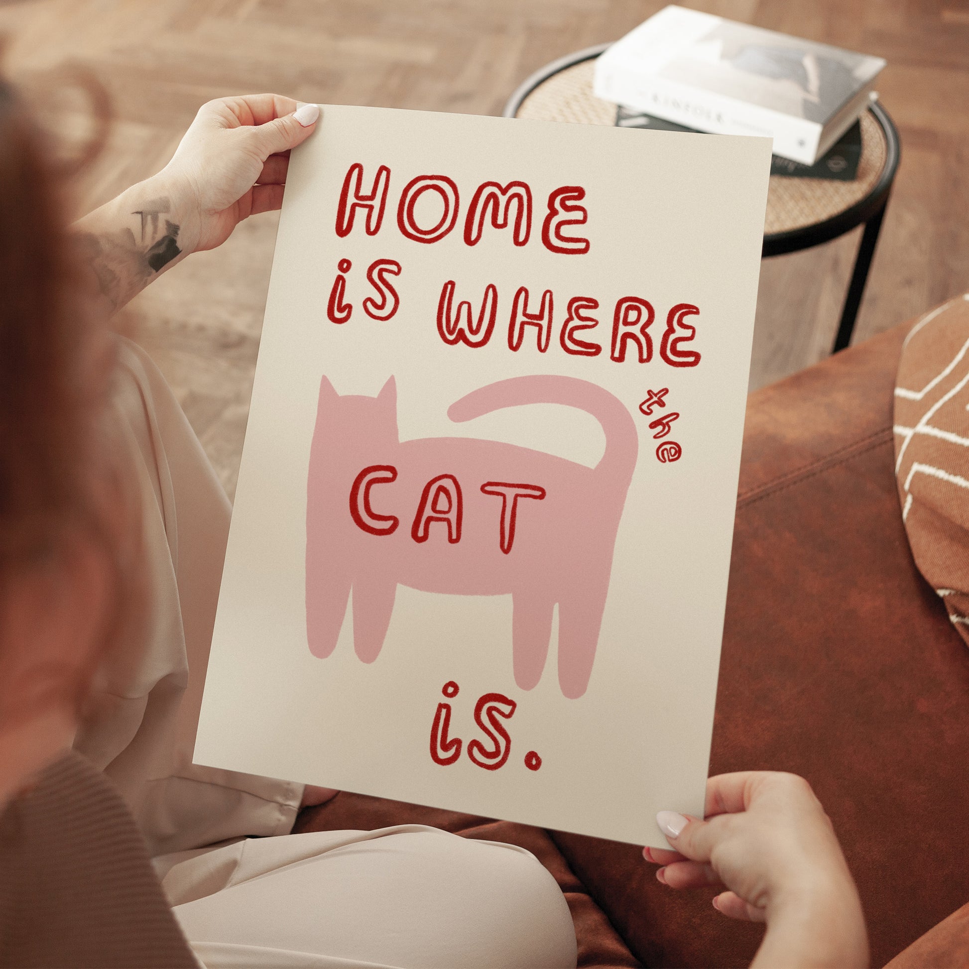 Home Is Where The Cat Is print: pink cat and red text, held up unframed