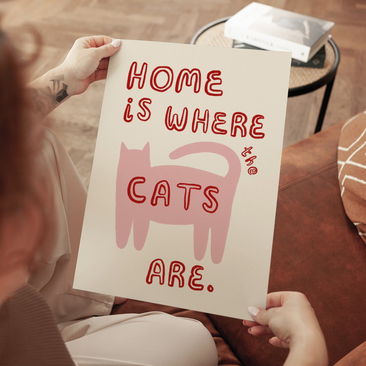 Katzenprint „Home is where the cats are“ in Händen, rosa Katze, rote Schrift, ungerahmt