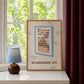 Framed cat spy print with window bars and 'NEIGHBOURHOOD SPY' text, blue accents on tabletop.