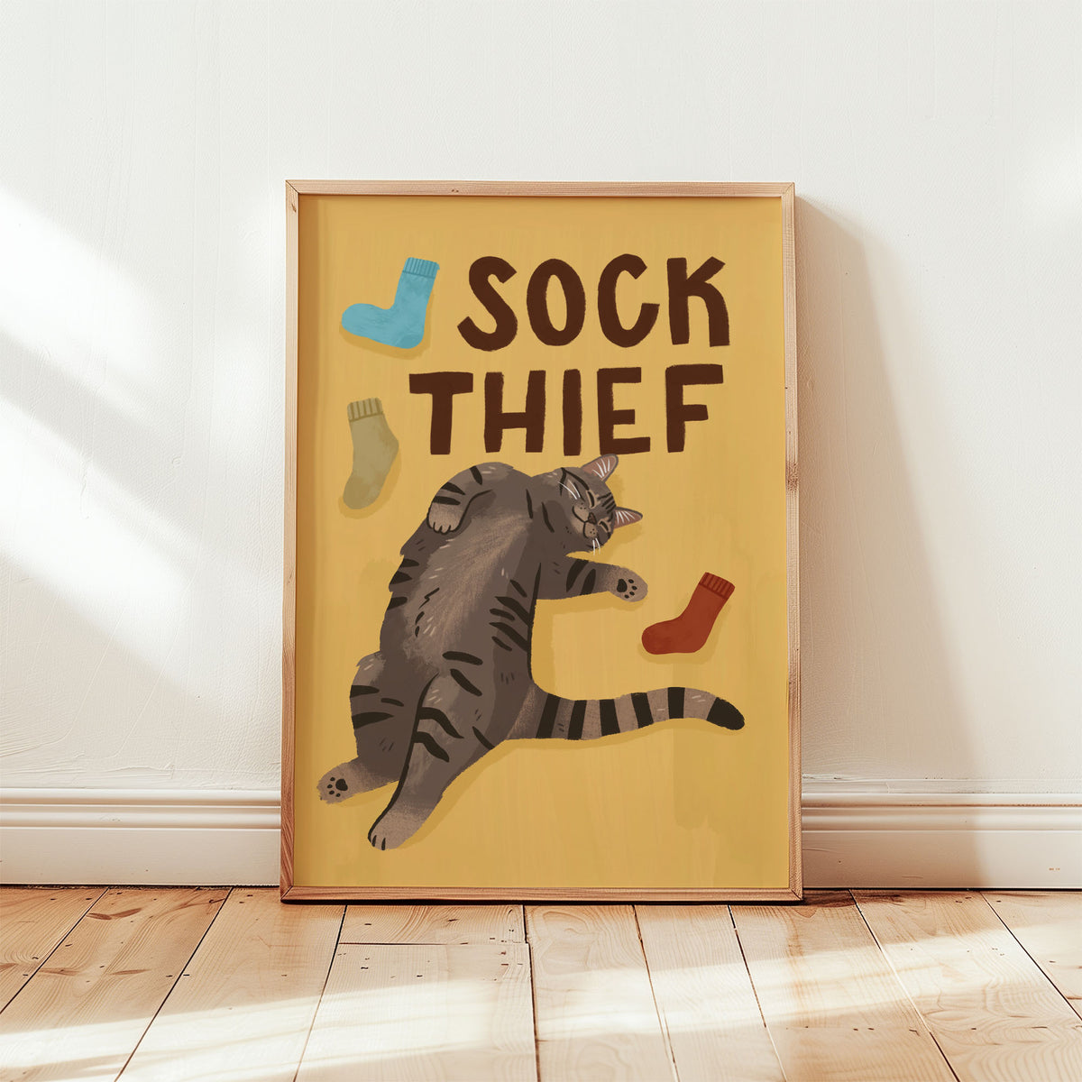 Framed cat print: 'SOCK THIEF' text with gray tabby cat and multi-color sock illustrations