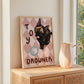 Cat print artwork on light wood surface, black kitten over tan-pink diamond pattern