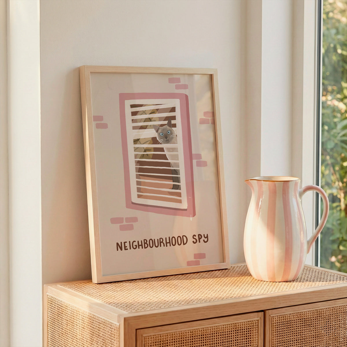 Framed cat spy print on stand with window bars and 'NEIGHBOURHOOD SPY' text, pink accents.