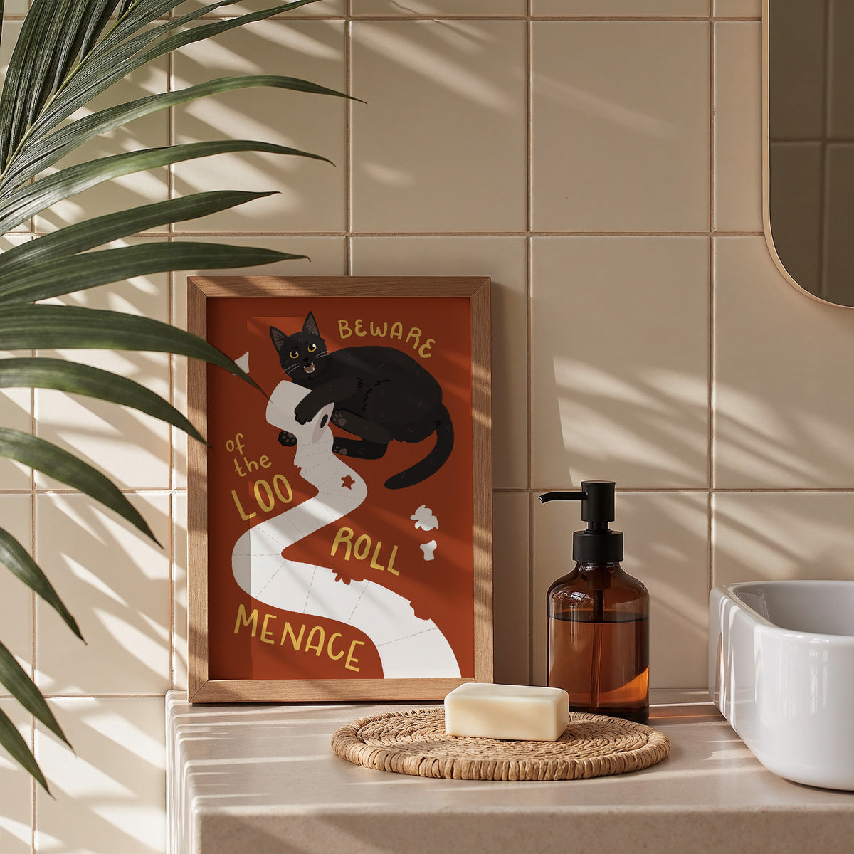 Cat toilet paper print in frame on countertop, orange background, houseplant nearby