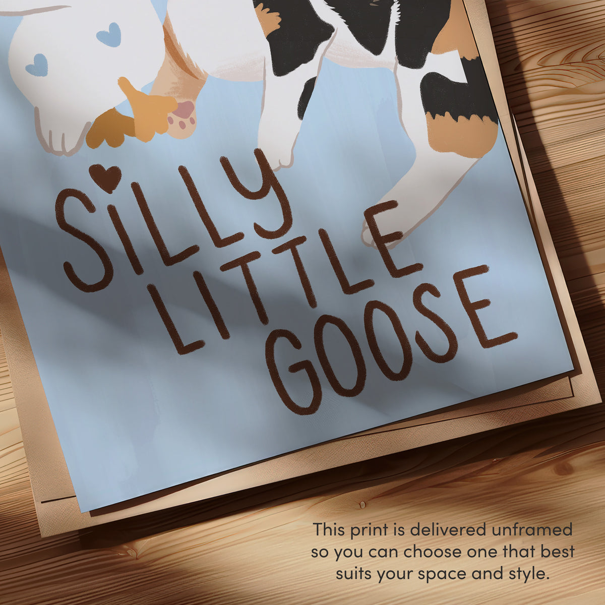 Close-up unframed “Silly Little Goose” text and cat/goose illustration on blue paper