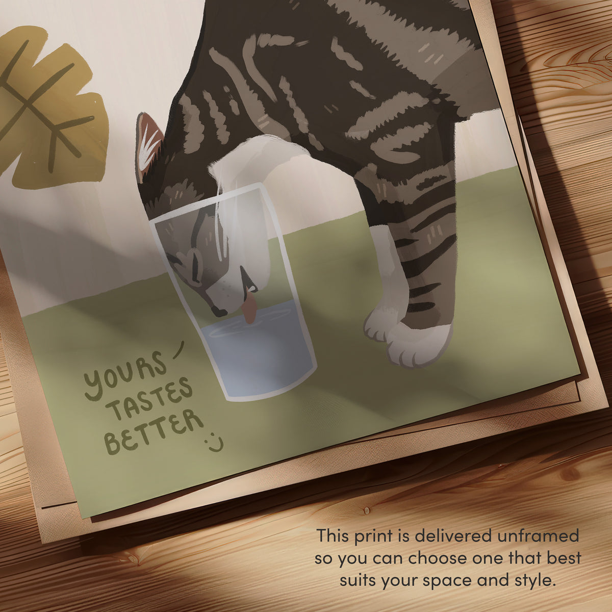 Close-up of unframed cat print: tabby cat and water glass with “YOURS TASTES BETTER”