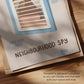 Close-up of framed cat spy print, 'NEIGHBOURHOOD SPY' text with window bars and blue accents.