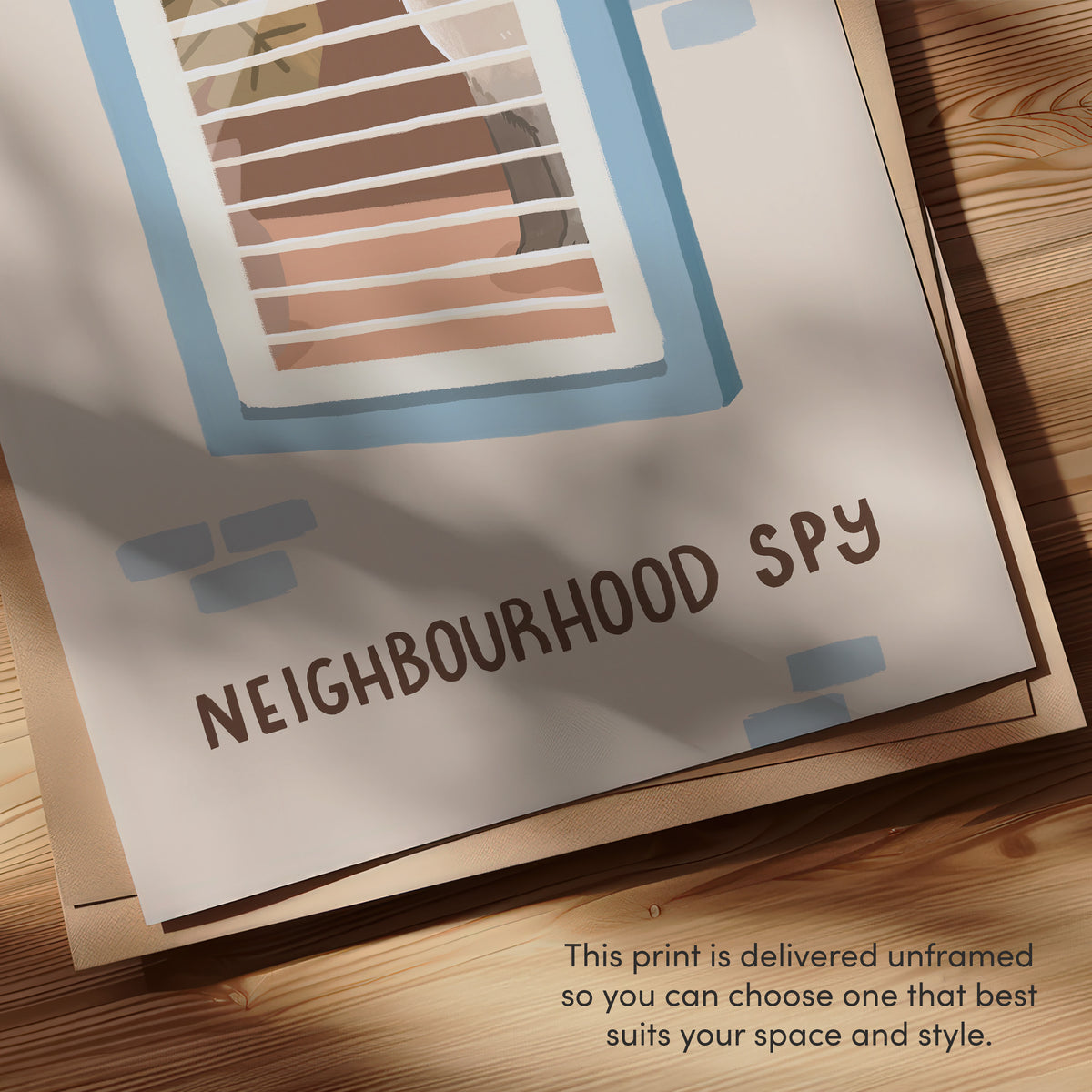 Close-up of framed cat spy print, 'NEIGHBOURHOOD SPY' text with window bars and blue accents.