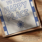 Close-up of Welcome to the Happy Place print, blue sun icon and lettering